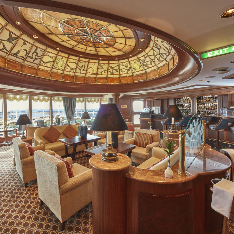 Luxury cruise lounge with armchairs beneath a stained-glass dome ceiling.