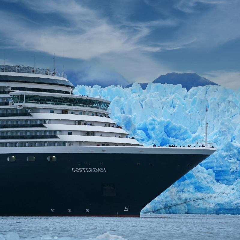 Close-up view of the Oosterdam cruise ship bow anchored beside a towering blue ice glacier.