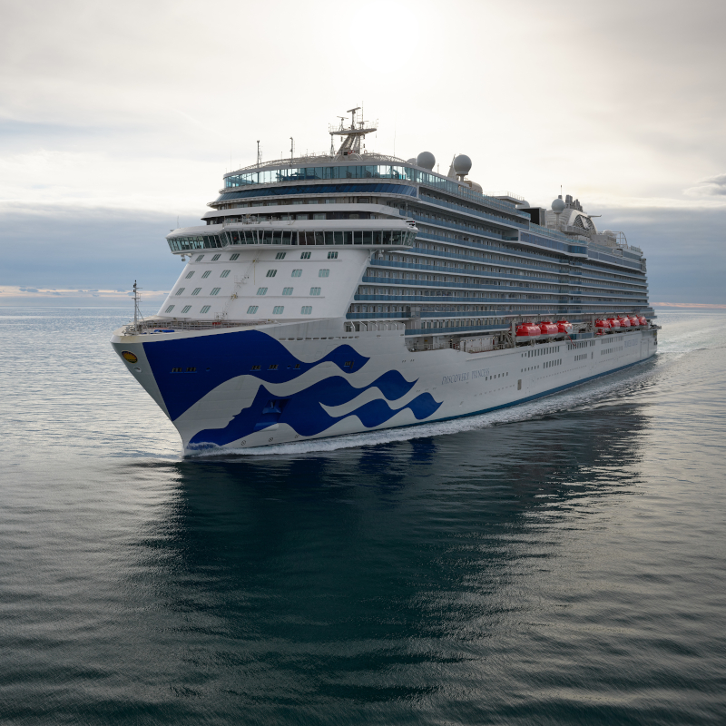 The Discovery Princess cruise ship sailing across calm open waters under a cloudy sky.