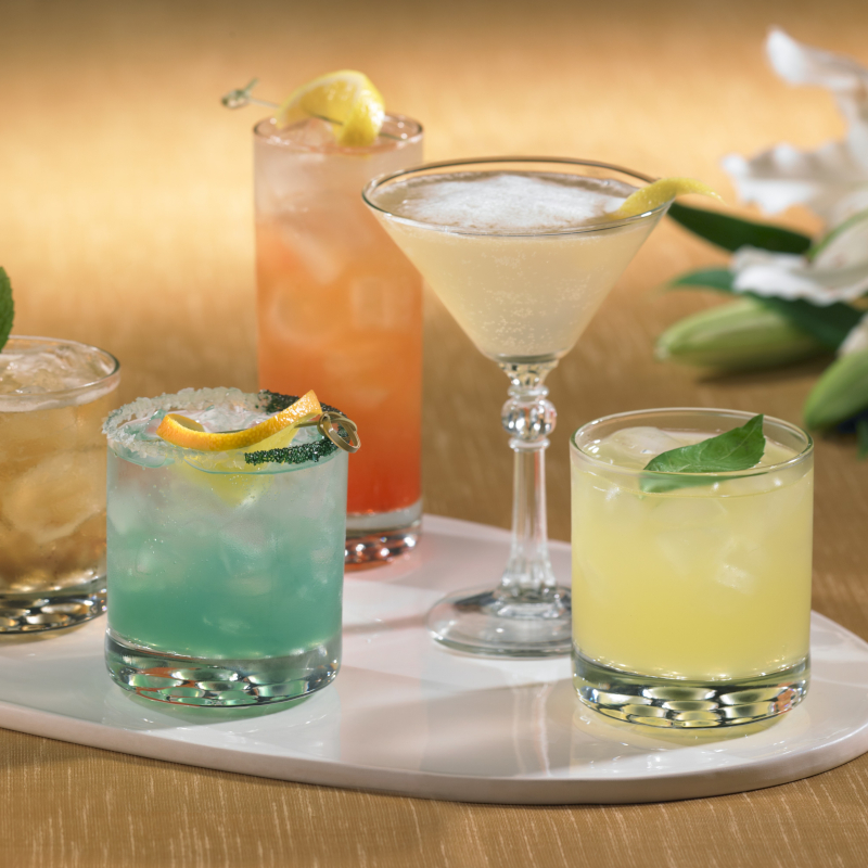 Selection of colourful handcrafted cocktails and mocktails served on a white platter.